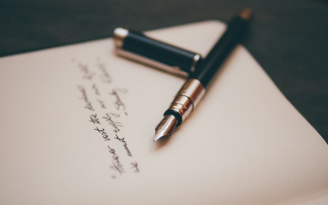 手書きの文字が並ぶ紙の上に置いた万年筆